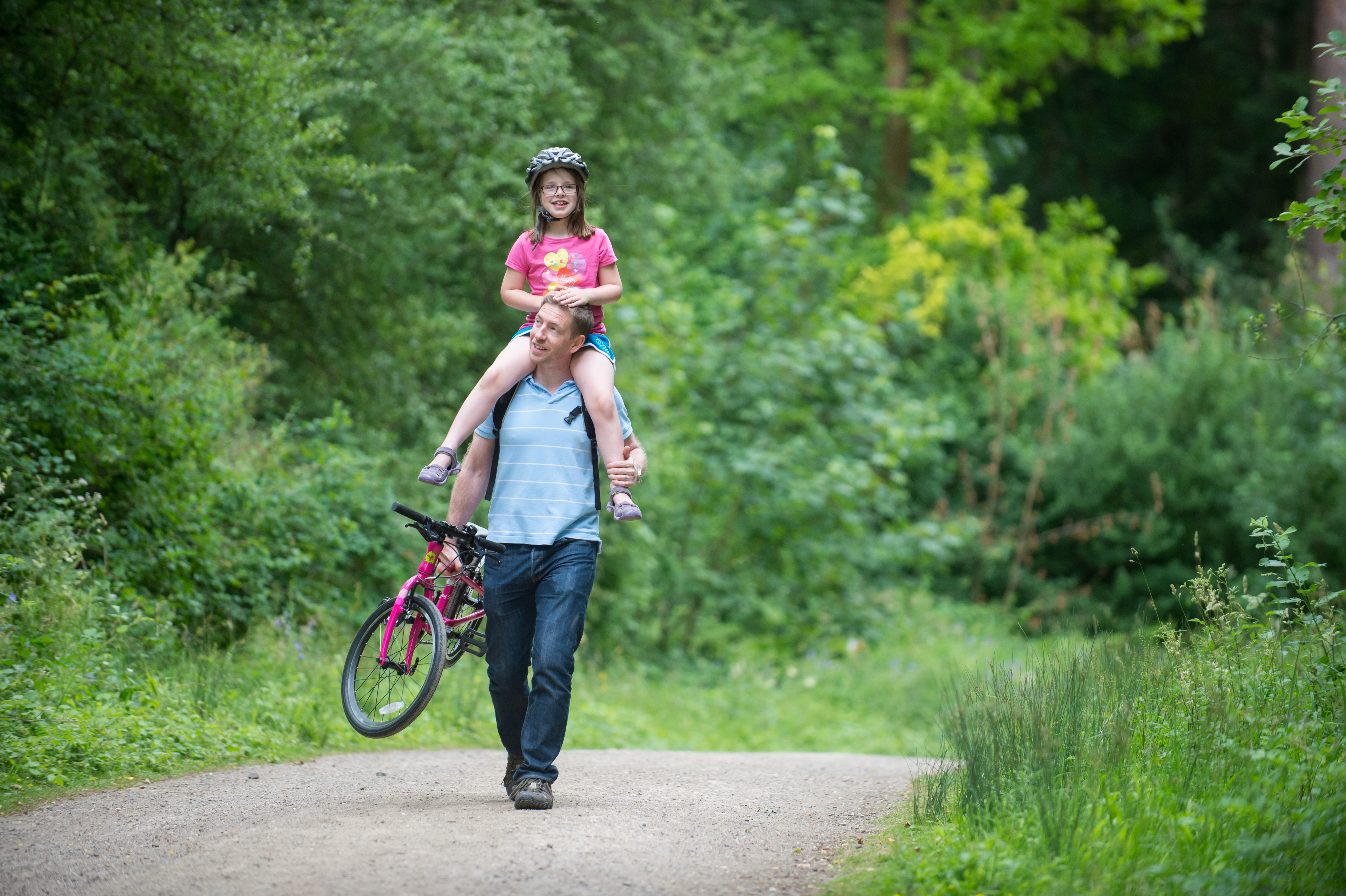 dad carrying daughter and bike
